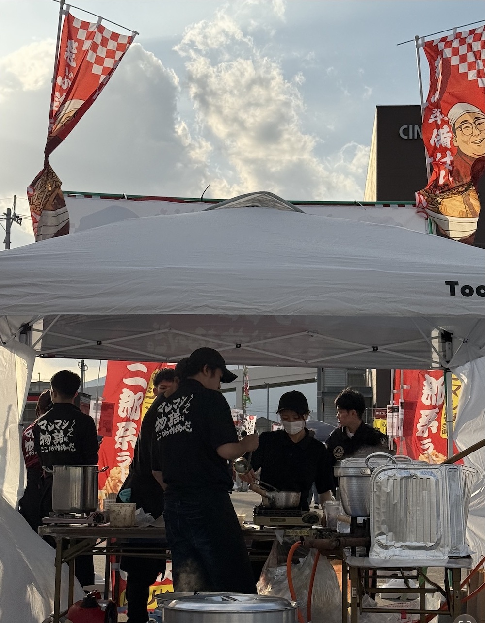 マシマシ物語ののぼりを掲げた出店ブースで調理する様子