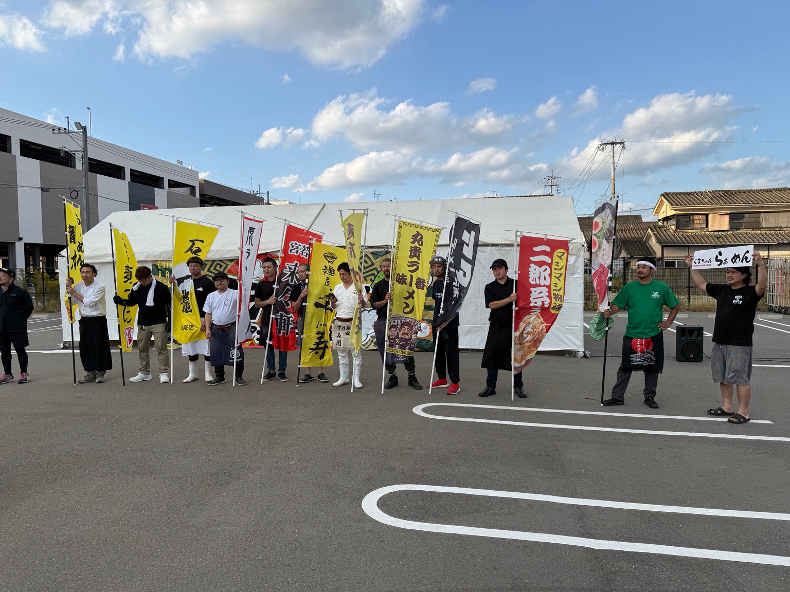 白いテントの前で出店者がのぼりと並ぶ集合写真。右寄りにマシマシ物語の赤いのぼり